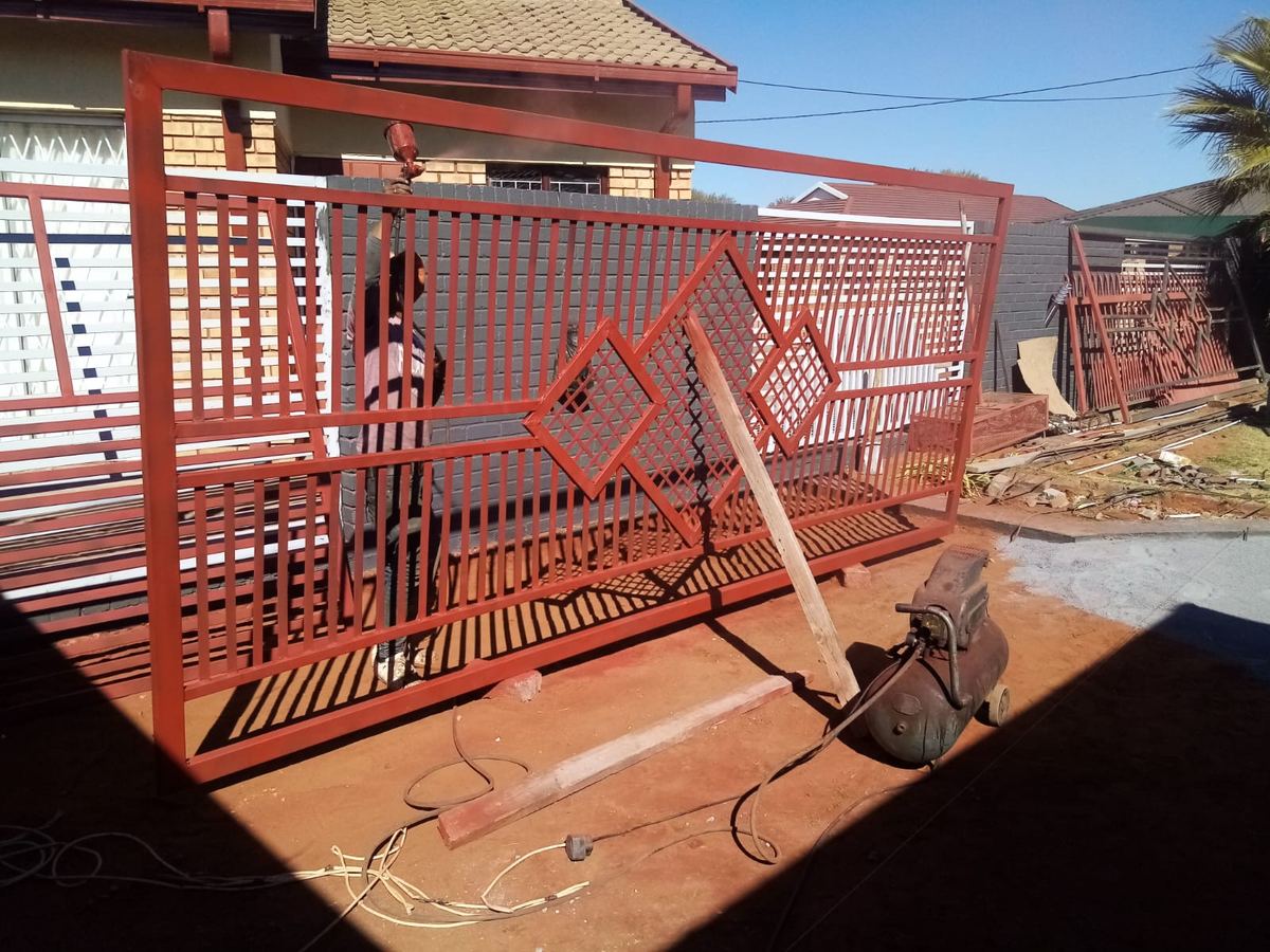 Red palisade driveway gates fabricated and installed by Bold T
