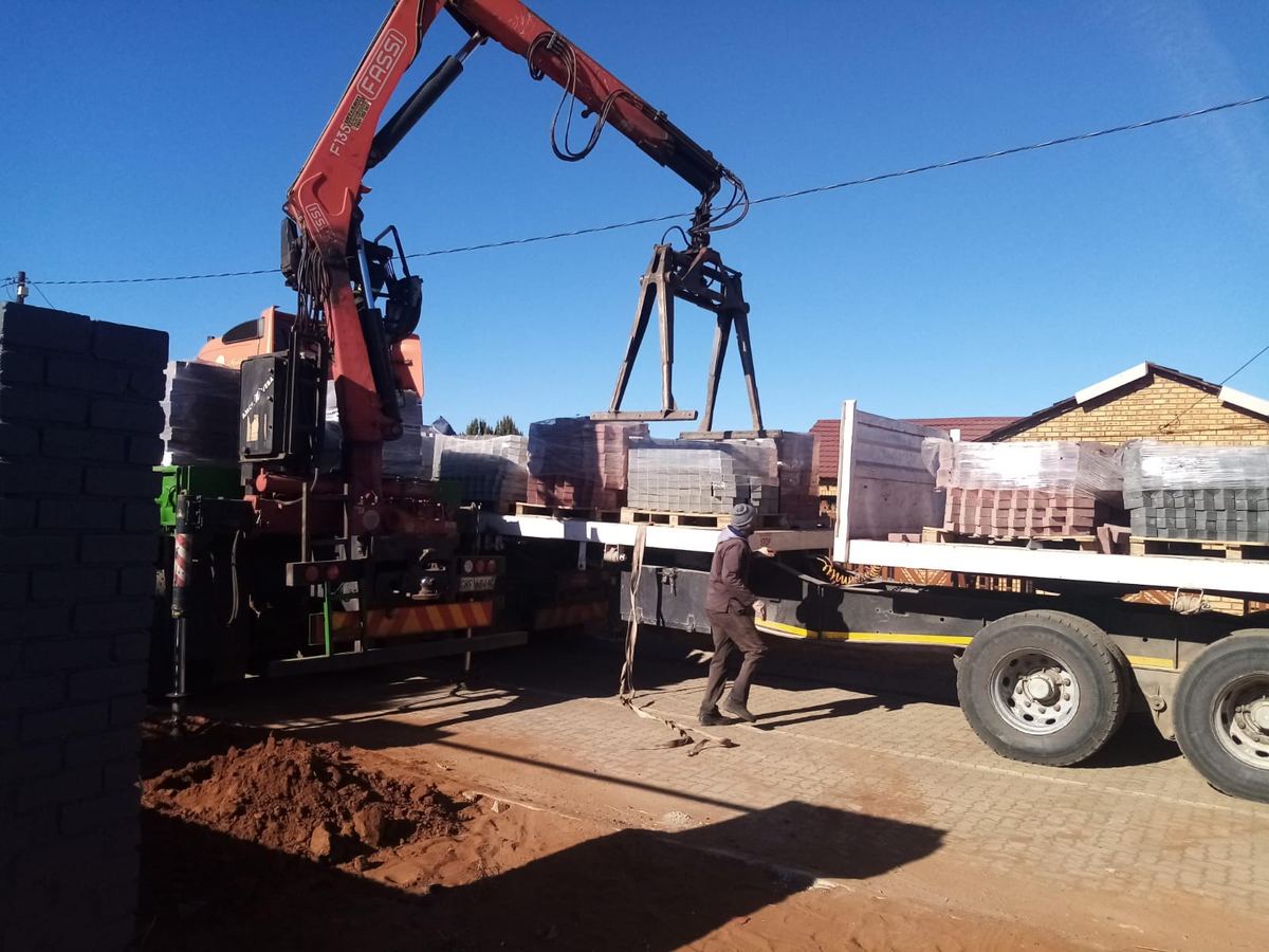 Truck-mounted crane offloading materials on a project site