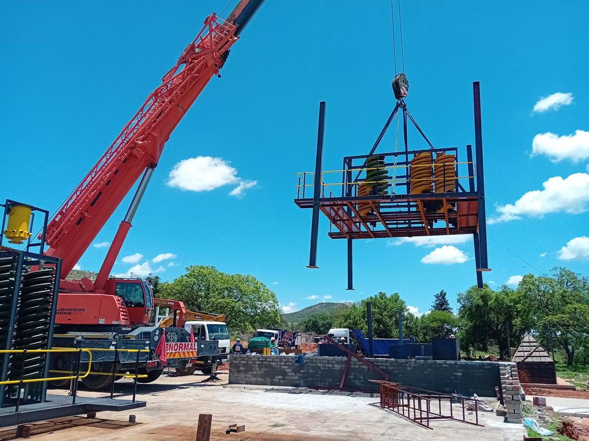 Mobile crane lifting a steel cage into position on site