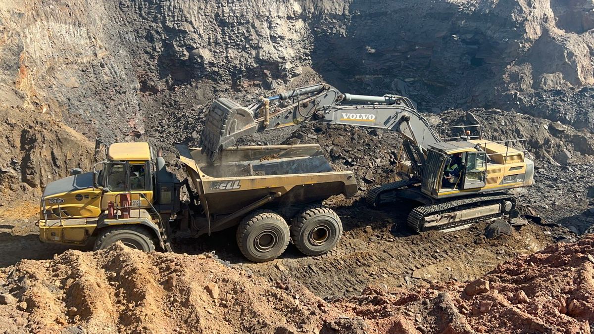 Articulated dump truck being loaded by an excavator in a mine pit