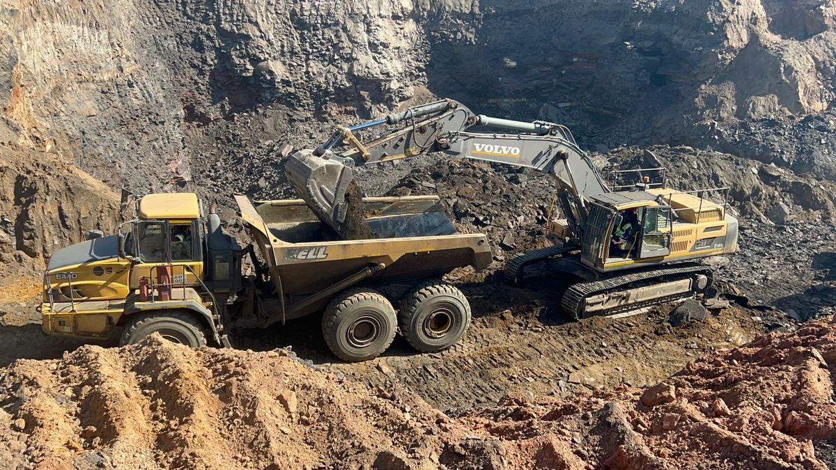 Excavator and articulated dump truck moving ore on a mining site
