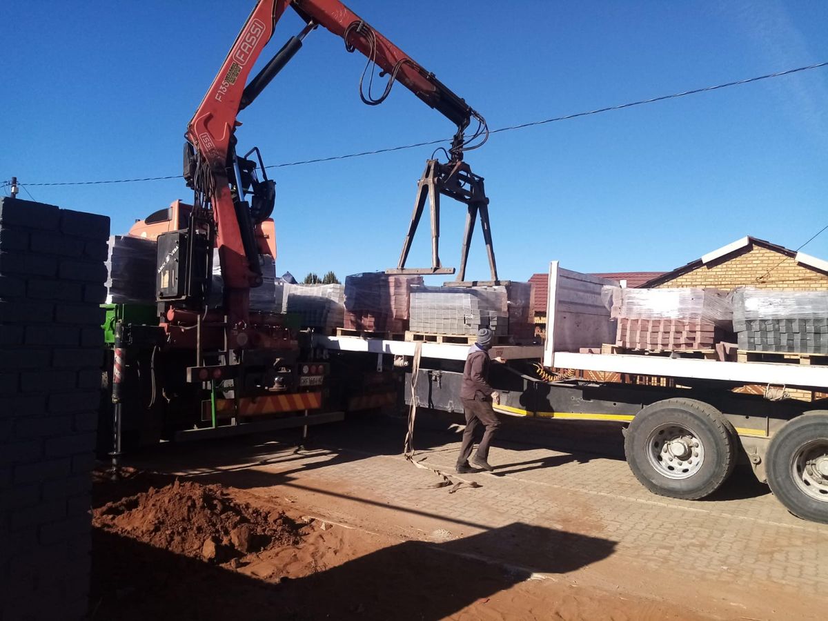 Truck-mounted crane offloading materials on a project site